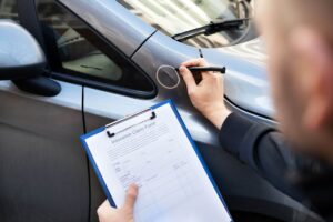 Mann macht Schadenaufnahme am Auto